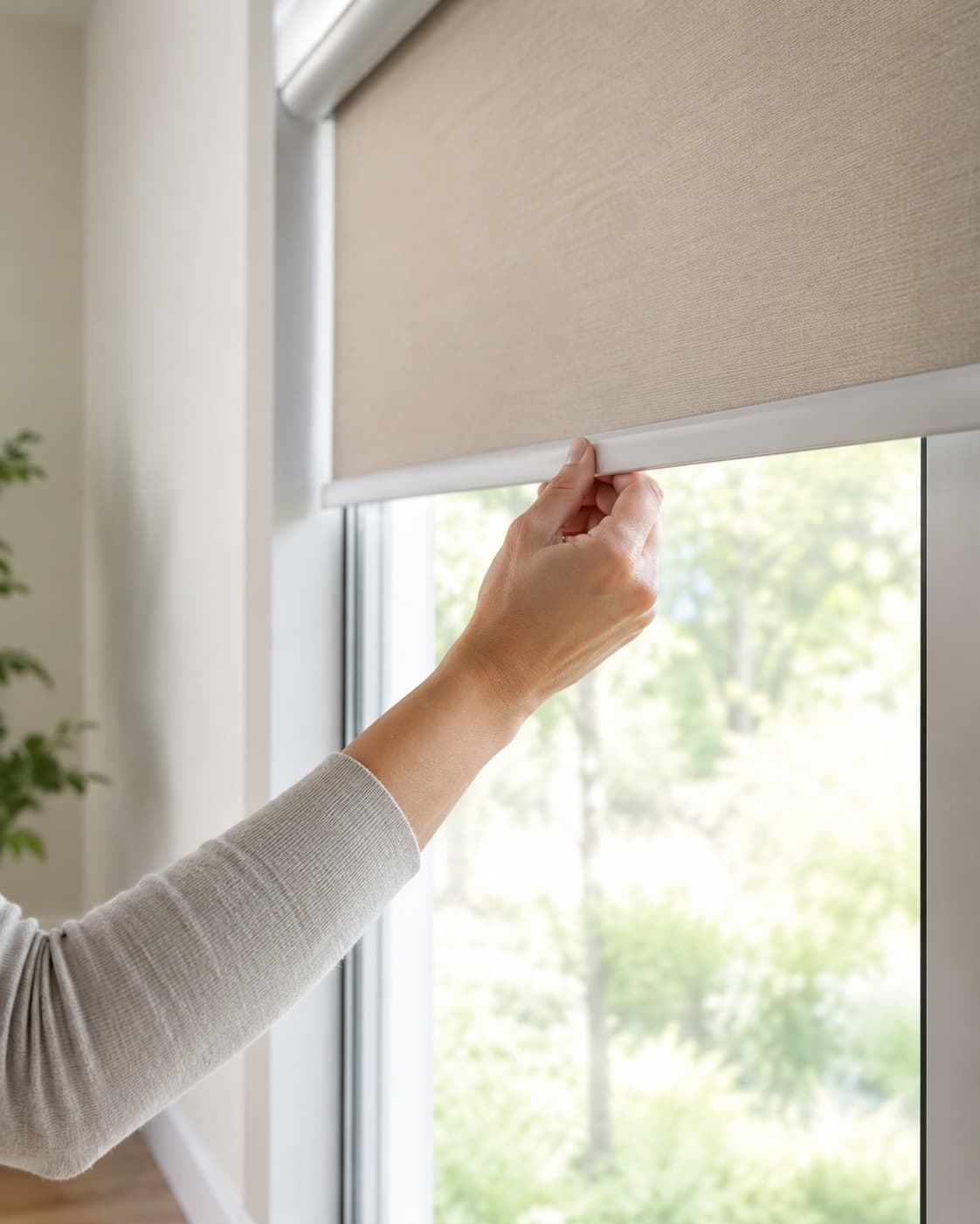 Homeowner adjusting a roller shade beside a bright window